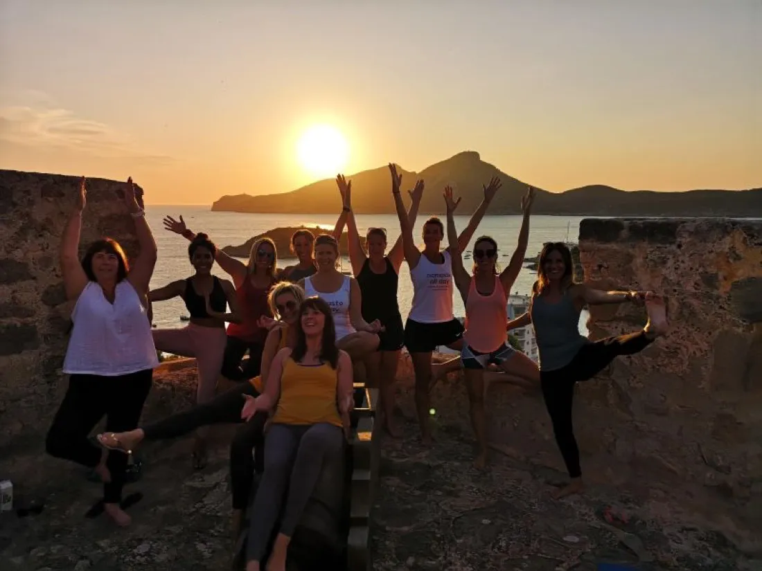 Sunset yoga poses on an old stone wall above the sea