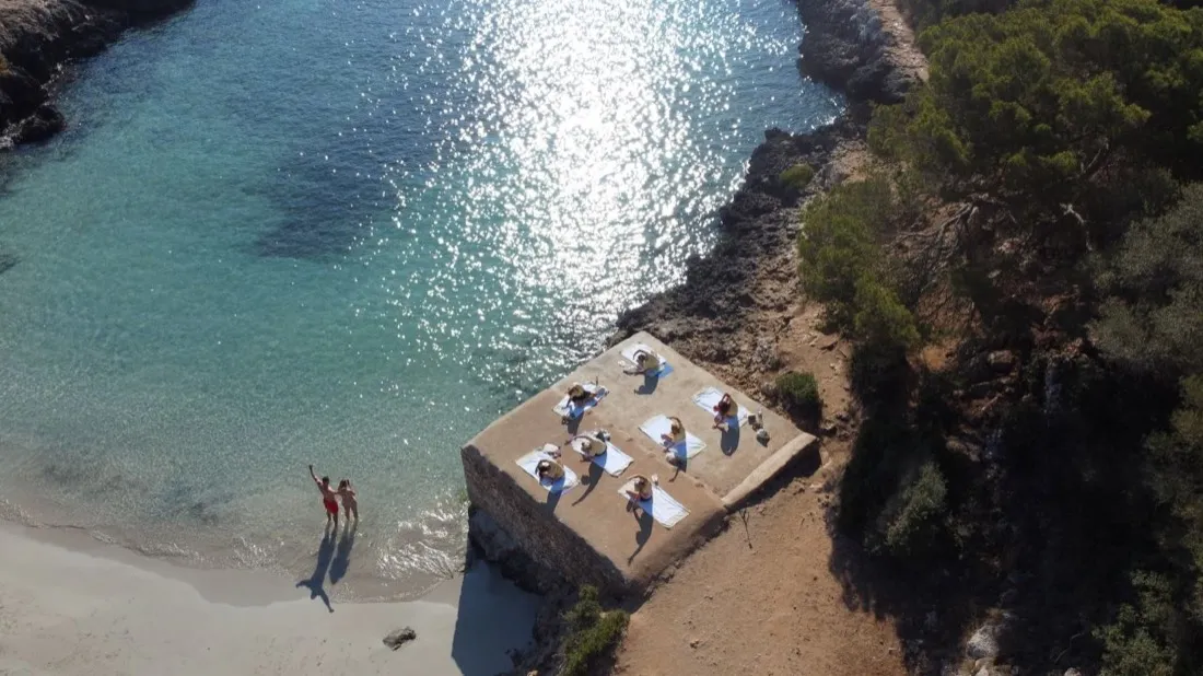 Aerial view of a morning yoga class beside a cove